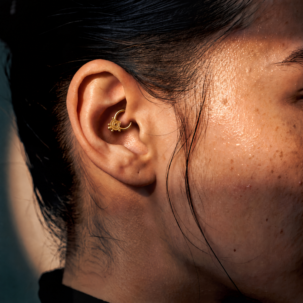 Anneau piercing Aural en titane gold, pendentif ciselé à pierre noire et perles dorées, porté au daith