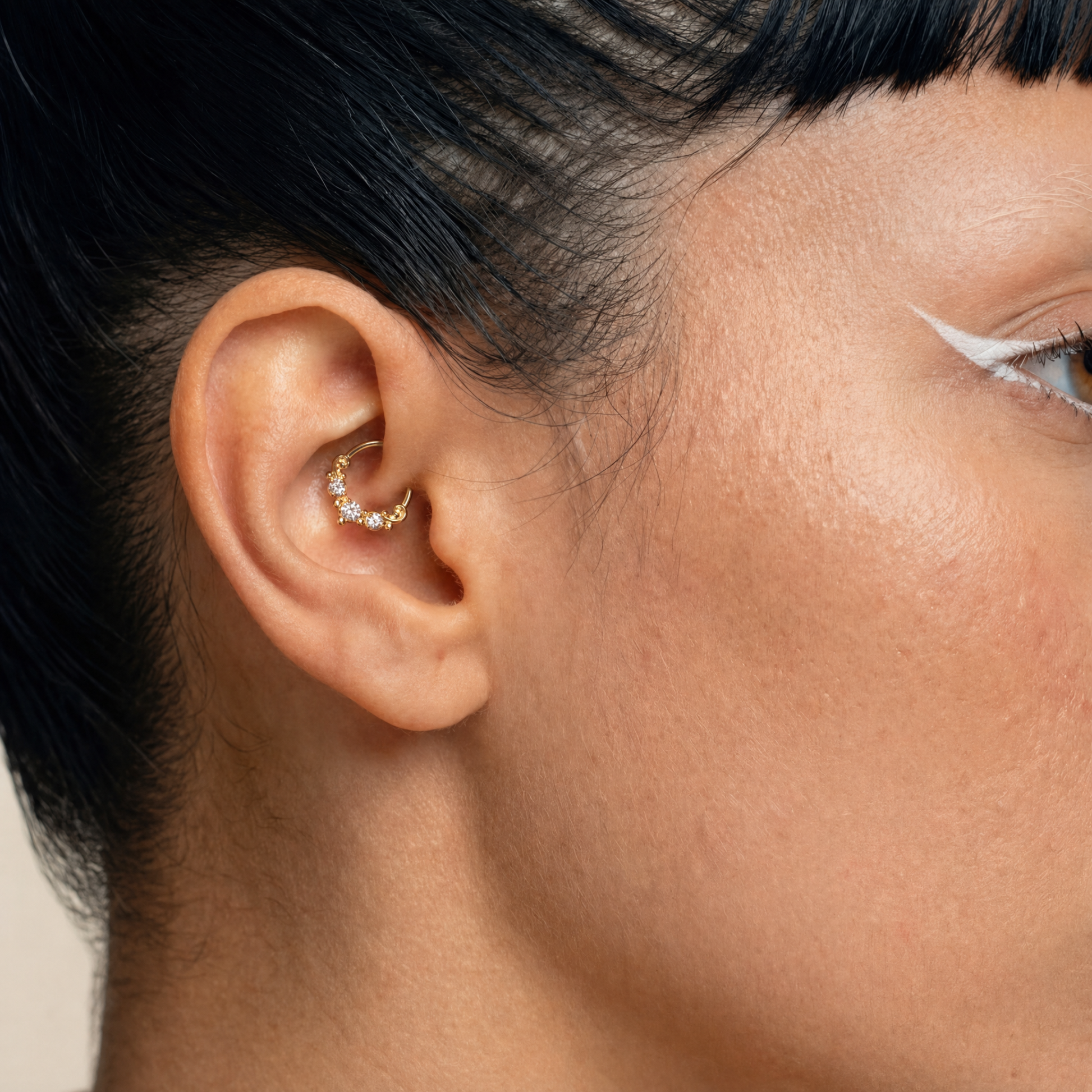 Anneau piercing Aurel porté au daith en titane gold avec trois zircons sertis et détails perlés