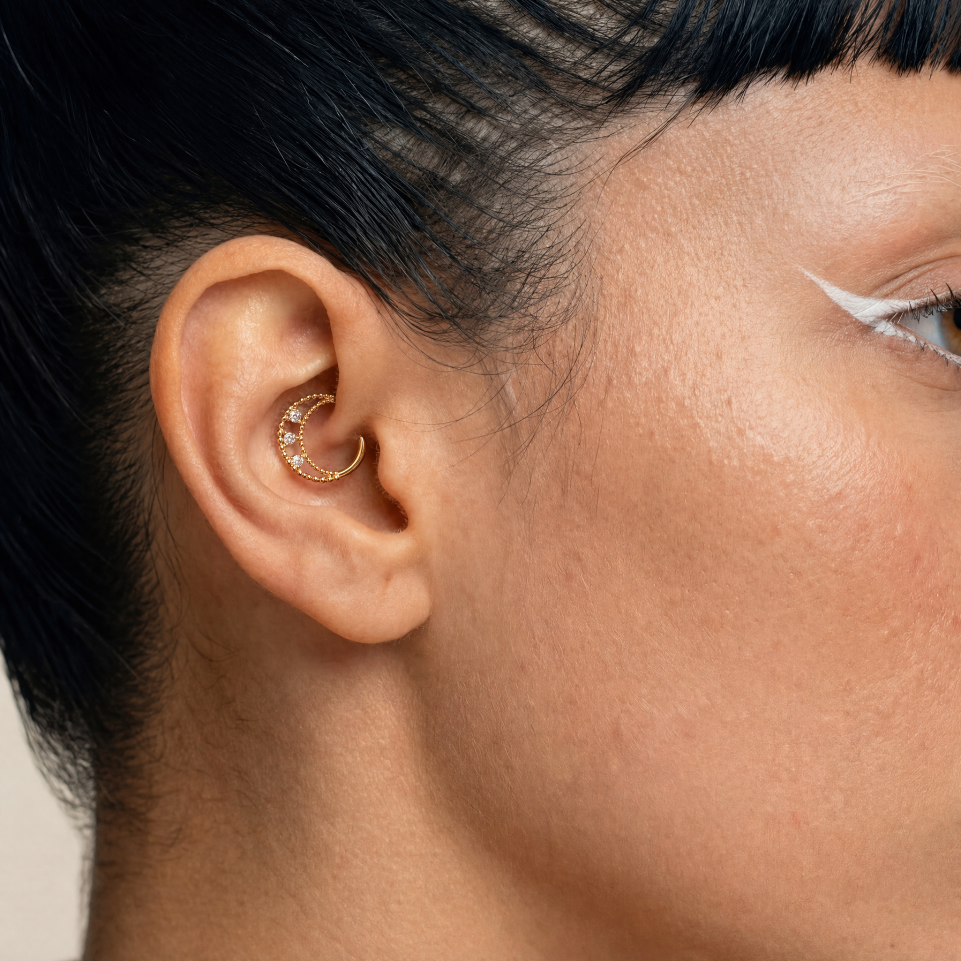 Anneau piercing Elio porté au daith en titane gold avec double rangée perlée et trois zircons sertis