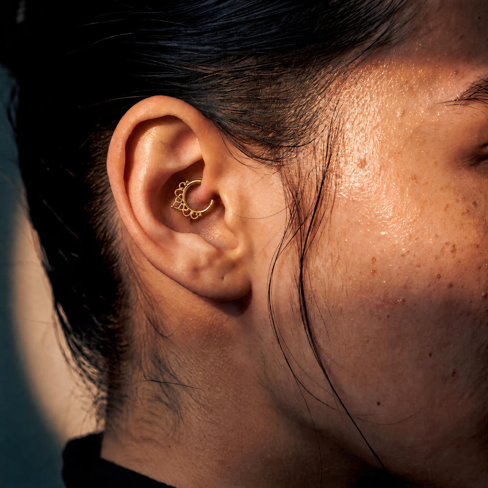 Anneau piercing Linea en titane gold, motif arrondi et géométrique avec pendentif en pointe, porté au daith