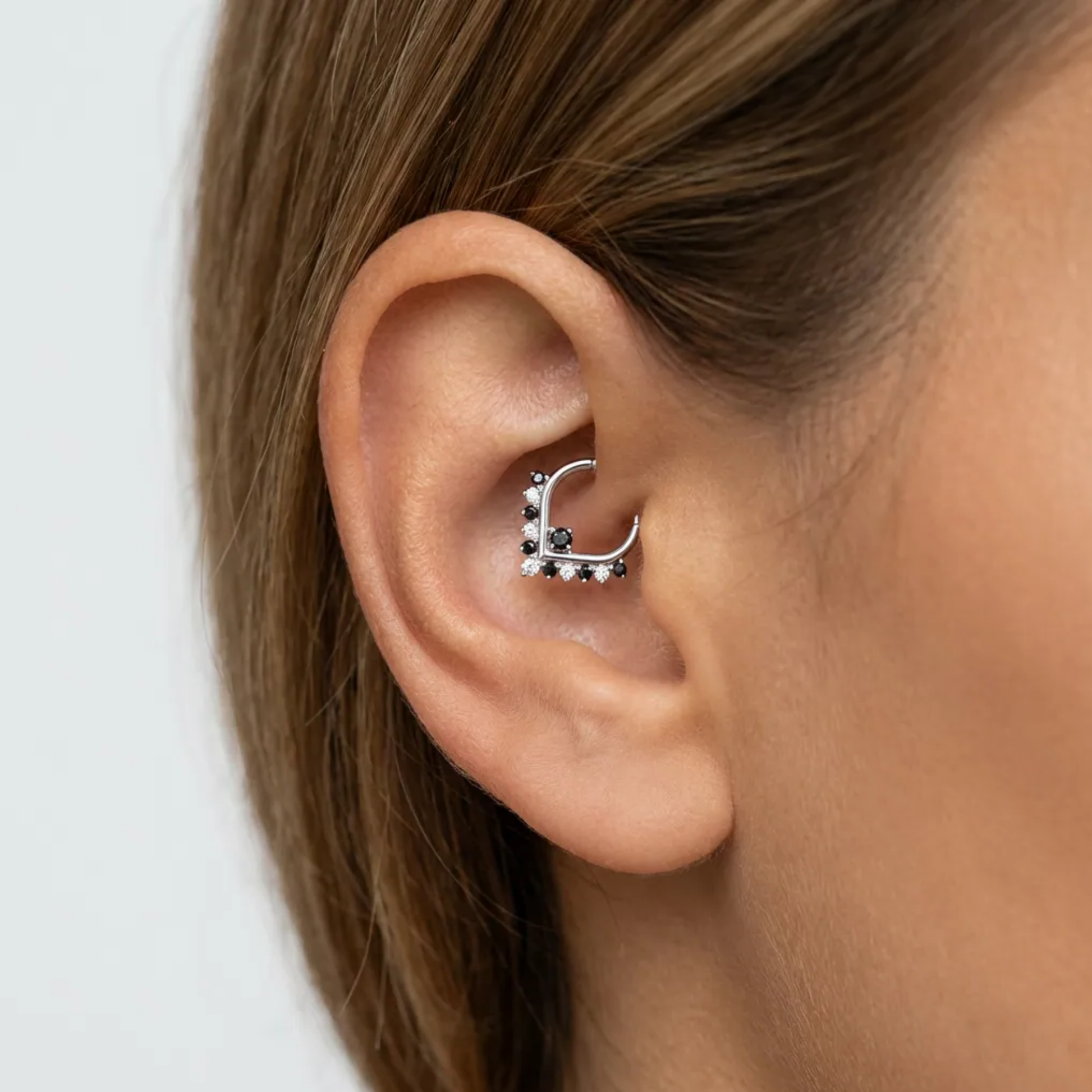 Anneau piercing Mena en titane avec zircons noir et blancs motif V porté au daith