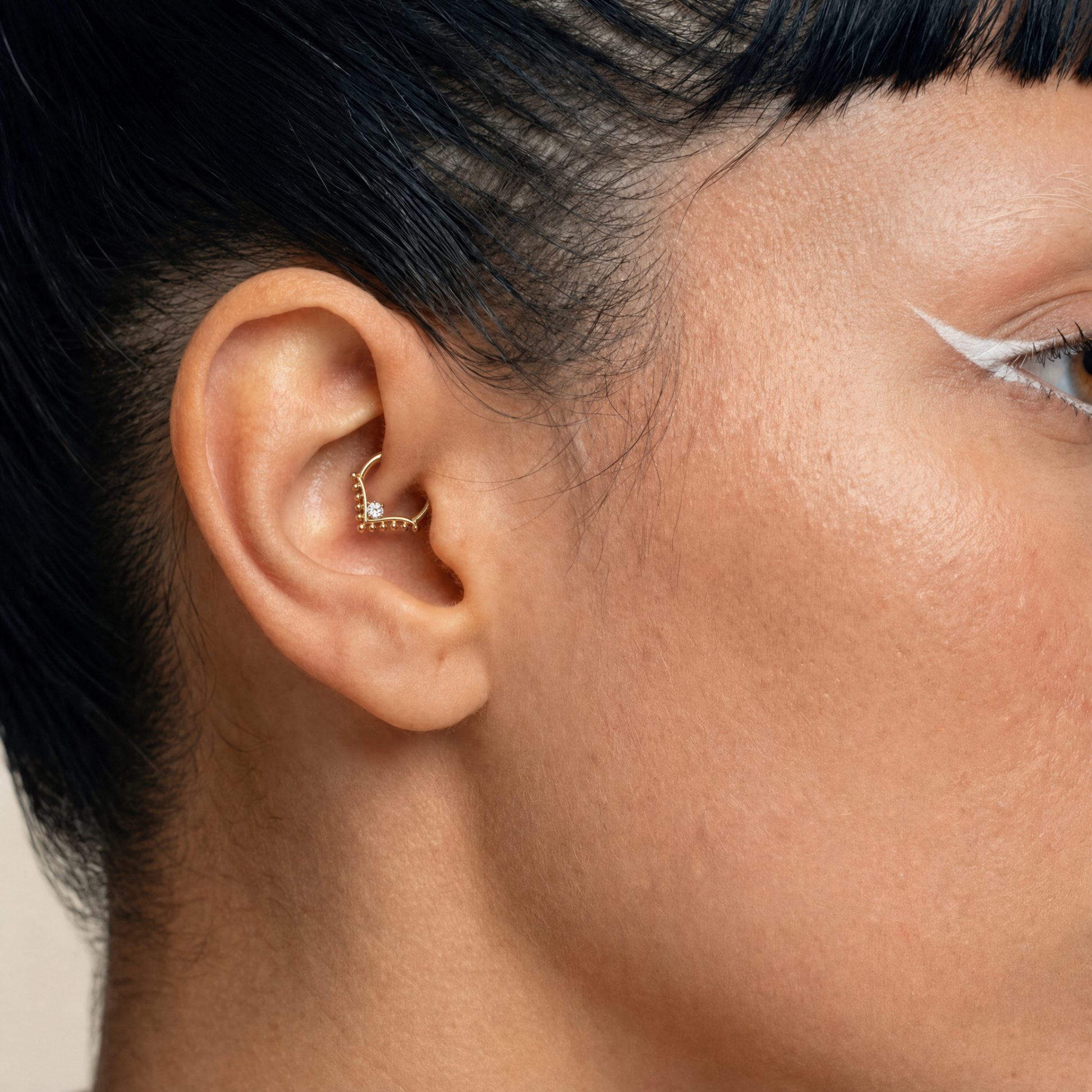 Anneau piercing Raya porté au daith en titane gold avec zircon central serti et détails perlés en forme de V
