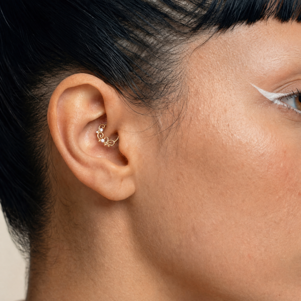 Anneau piercing Solis porté au daith en titane gold avec courbes élégantes et zircons sertis