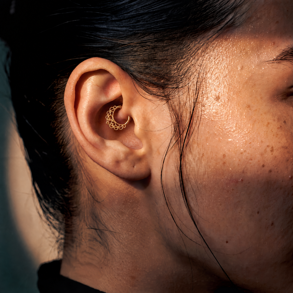 Anneau piercing Vera en titane gold, motif ajouré aux lignes arrondies, porté au daith