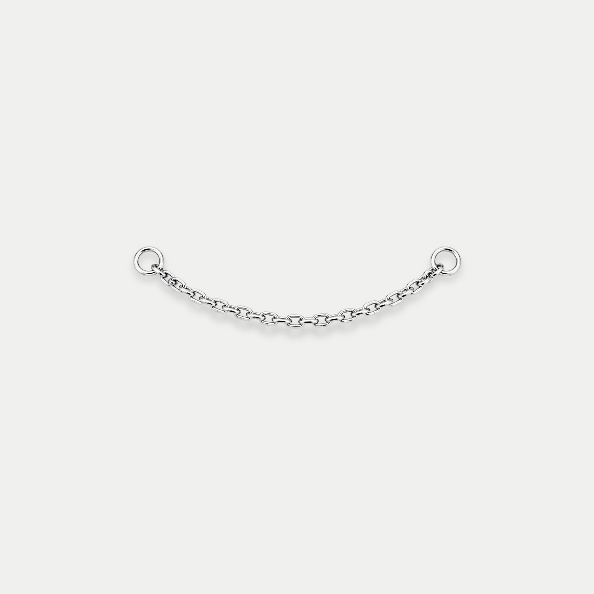 Chaîne de piercing en titane argenté avec deux anneaux aux extrémités, reliant deux points de perçage