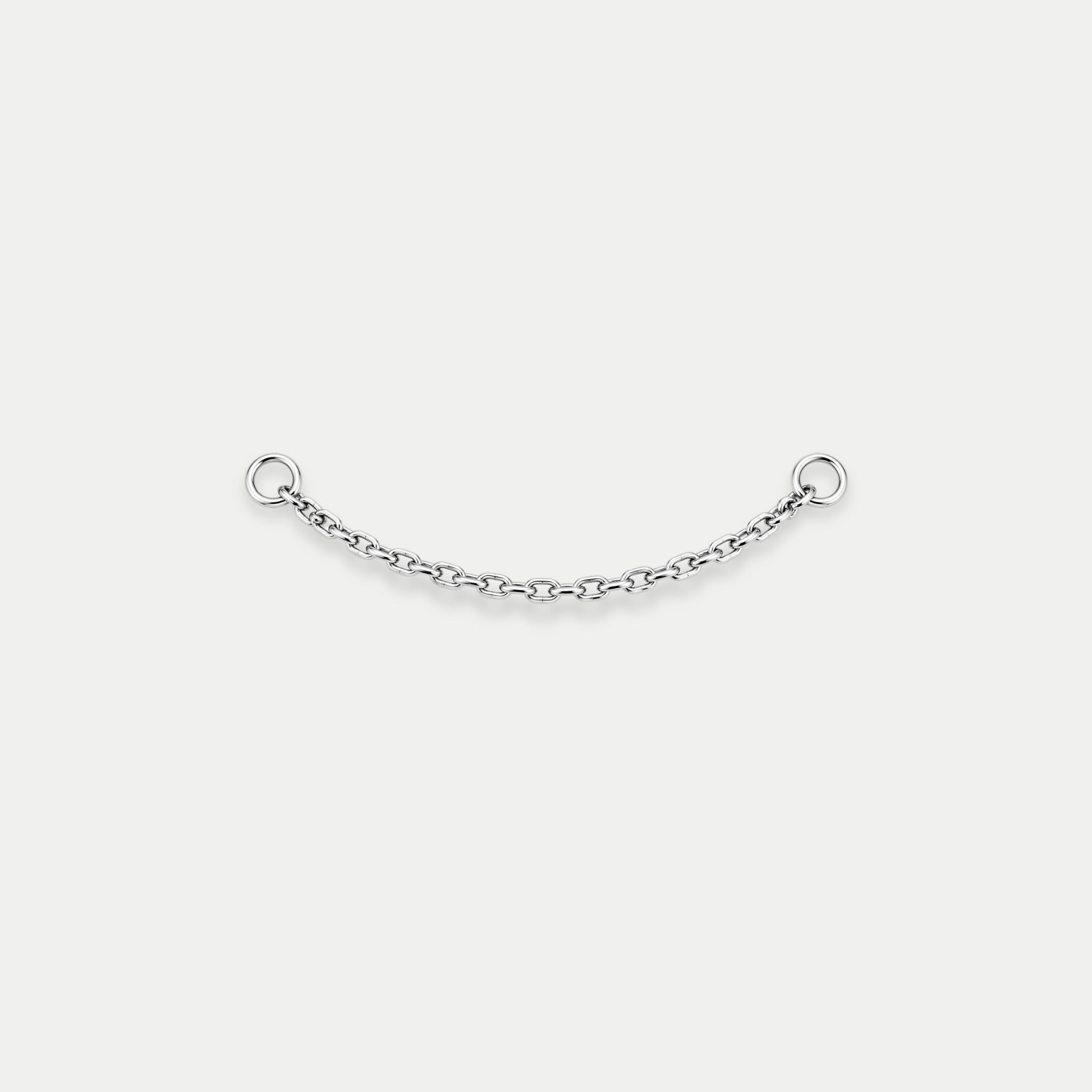Chaîne de piercing en titane argenté avec deux anneaux aux extrémités, reliant deux points de perçage