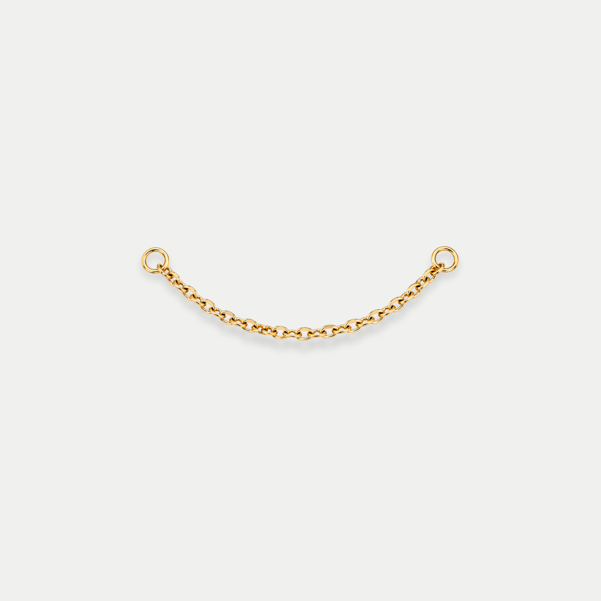 Chaîne de piercing en titane gold avec deux anneaux aux extrémités reliant deux piercings