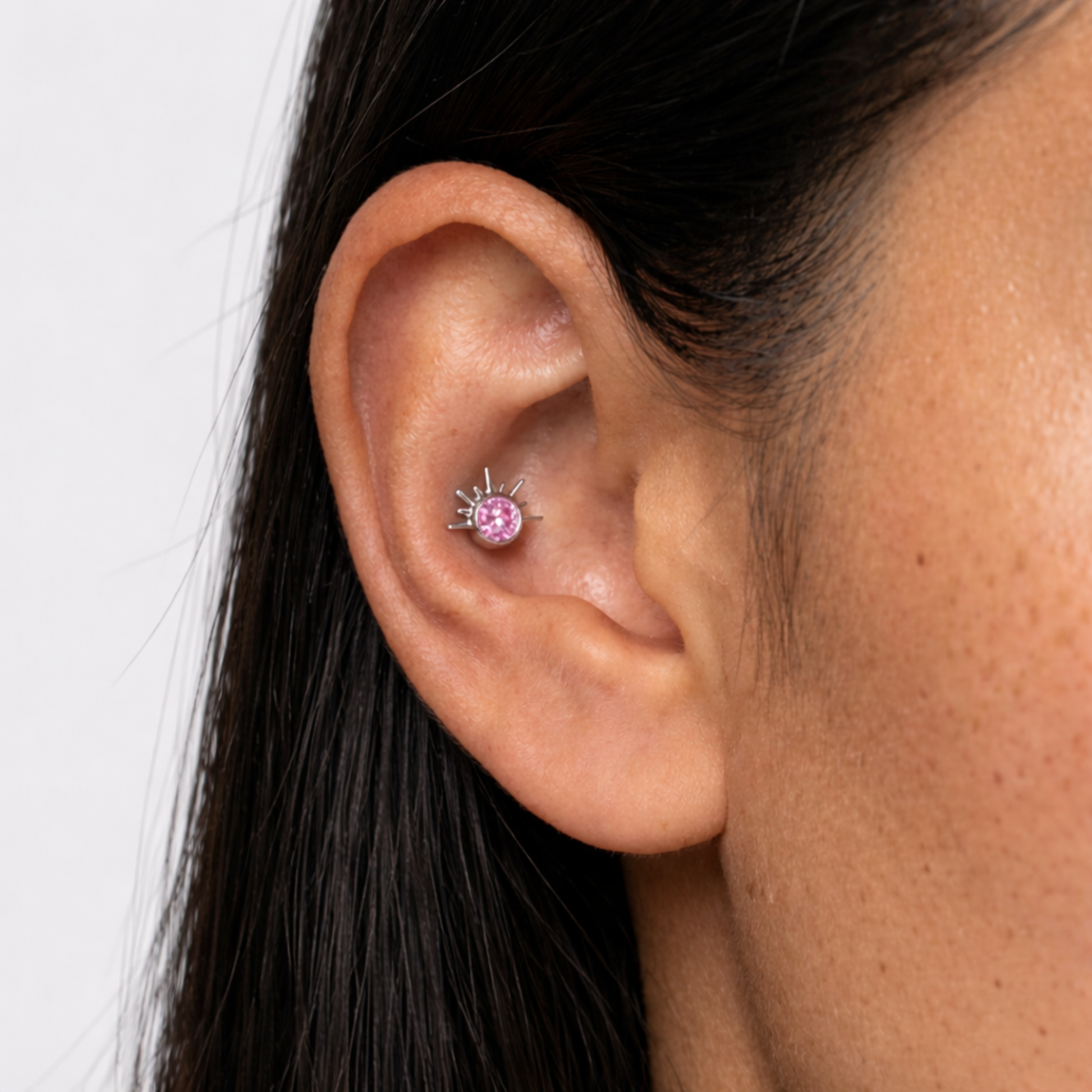 Embout piercing Elio en titane avec zircon rose effet soleil porté au tragus