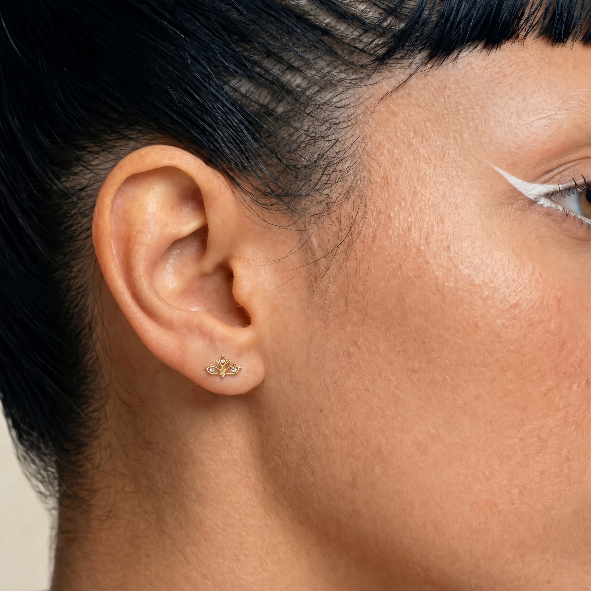Embout piercing Helia porté au lobe en titane gold avec trois zircons sertis et motif ajouré délicat